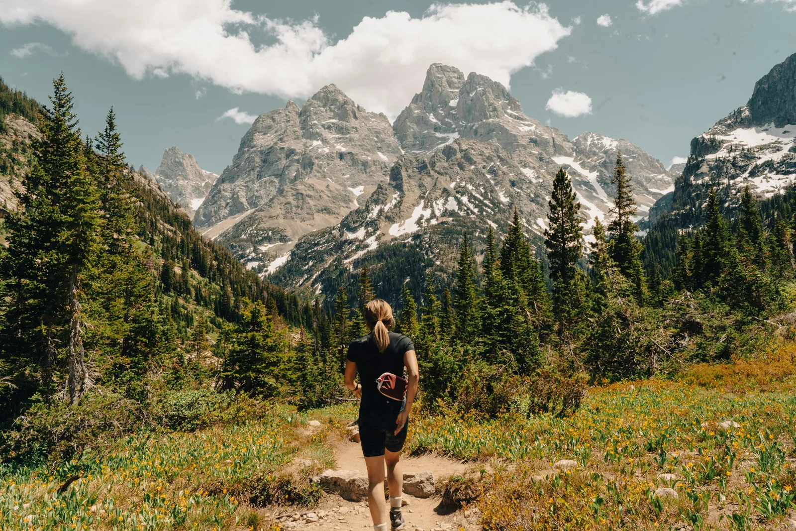 Woman hiking toward dramatic mountain peaks