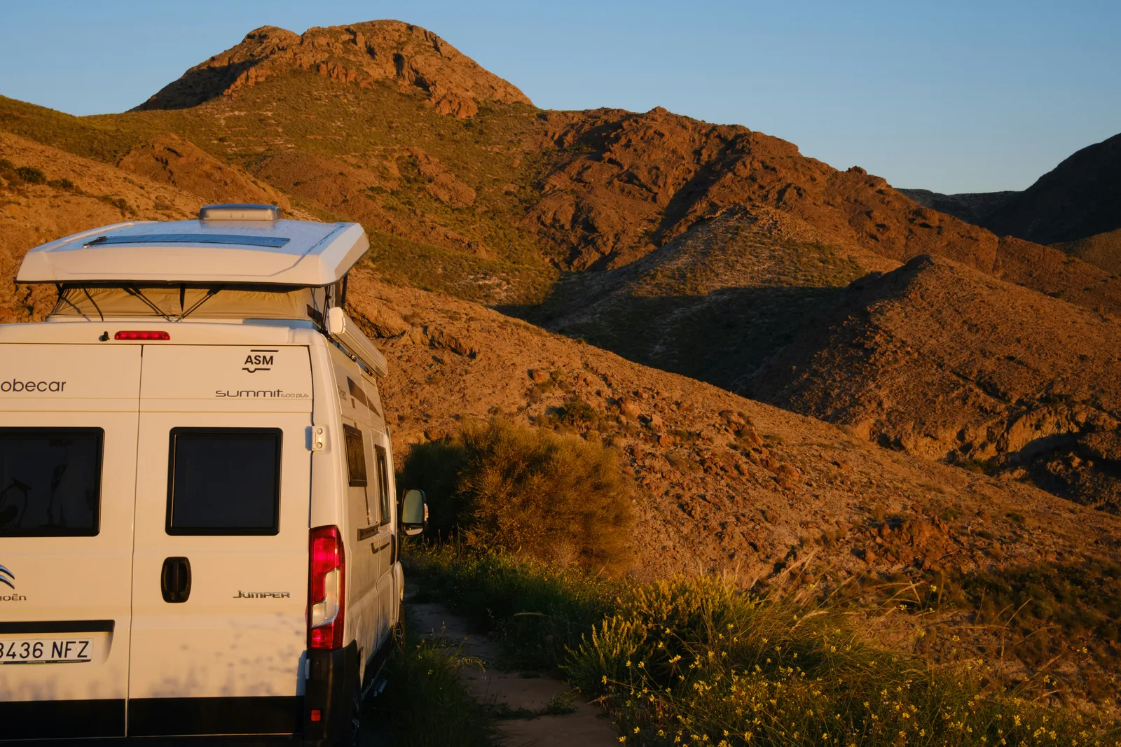 Camper van parked in a mountain landscape at sunset